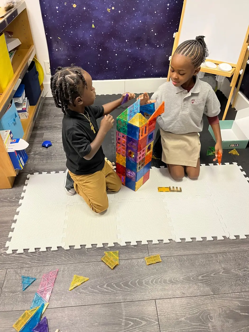 Students building a structure with magnetic tiles