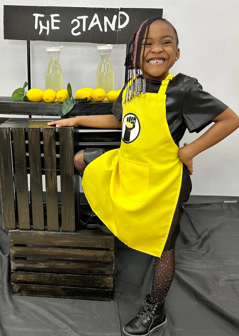 Smiling student wearing a yellow The Stand apron